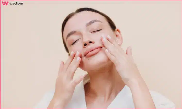 women applying moisturizer to her face, preparing a smooth base for makeup application.